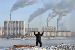 An elderly man exercises in the morning as he faces chimneys emitting smoke behind buildings across the Songhua river in Jilin, Jilin province, February 24, 2013. China's new rulers will focus on consumer-led growth to narrow the gap between rich and poor while taking steps to curb pollution and graft, the government said on Tuesday, tackling the main triggers for social unrest in the giant nation. Picture taken February 24, 2013. REUTERS/Stringer (CHINA - Tags: ENVIRONMENT BUSINESS POLITICS) CHINA OUT. NO COMMERCIAL OR EDITORIAL SALES IN CHINA - RTR3EL55